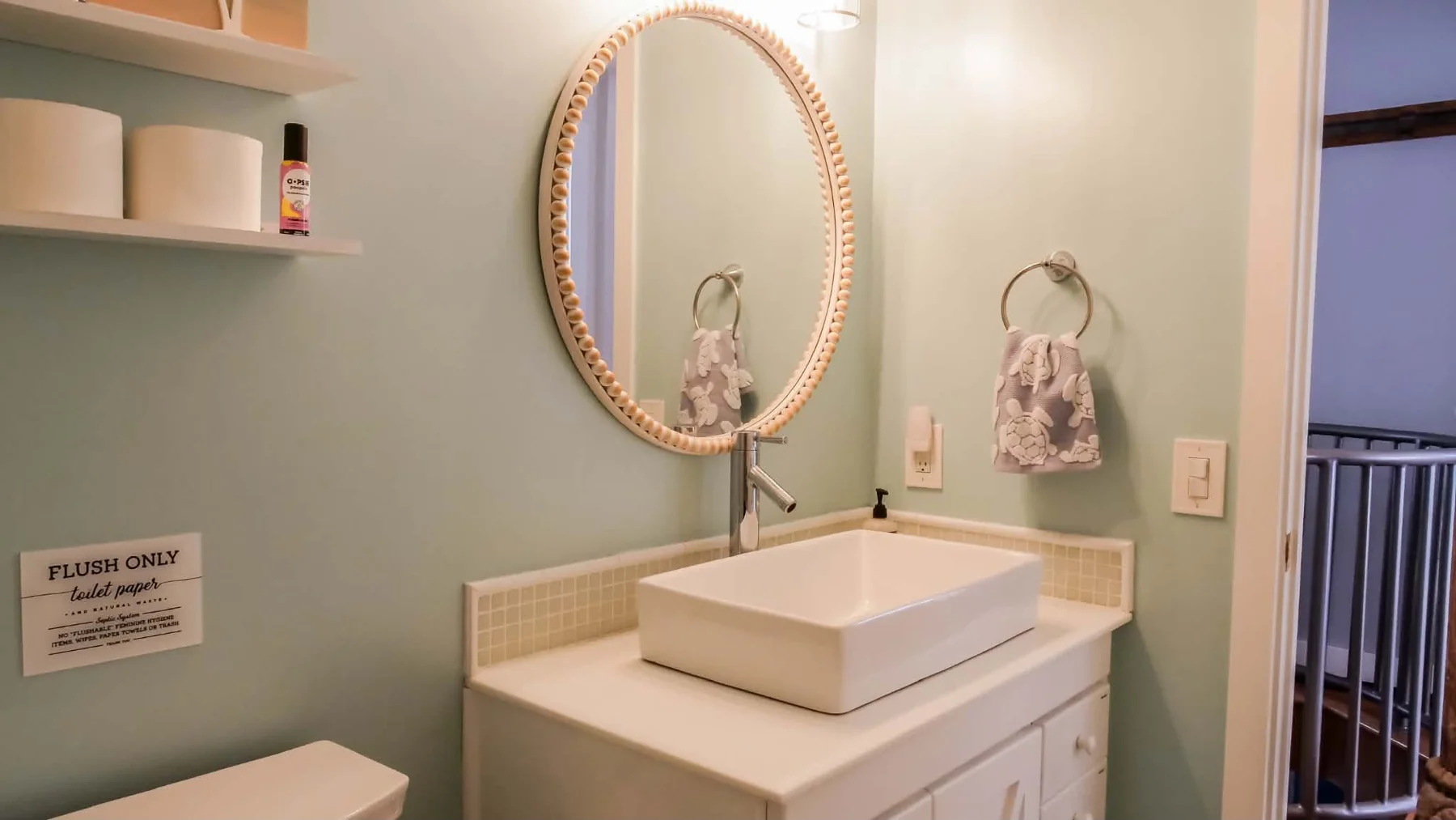 Bathroom with round mirror and pale green walls
