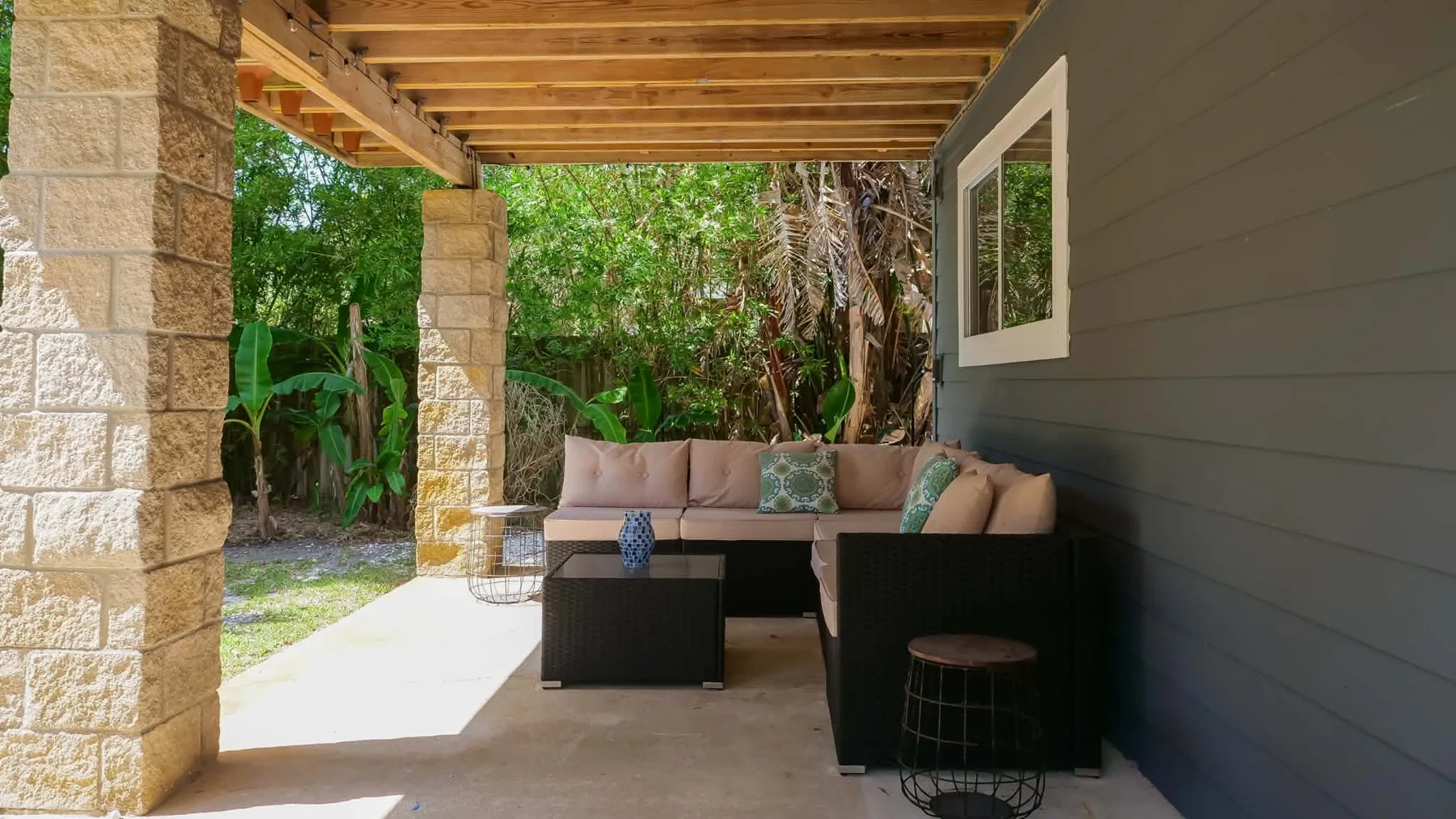 Covered patio with comfortable seating and tropical plants