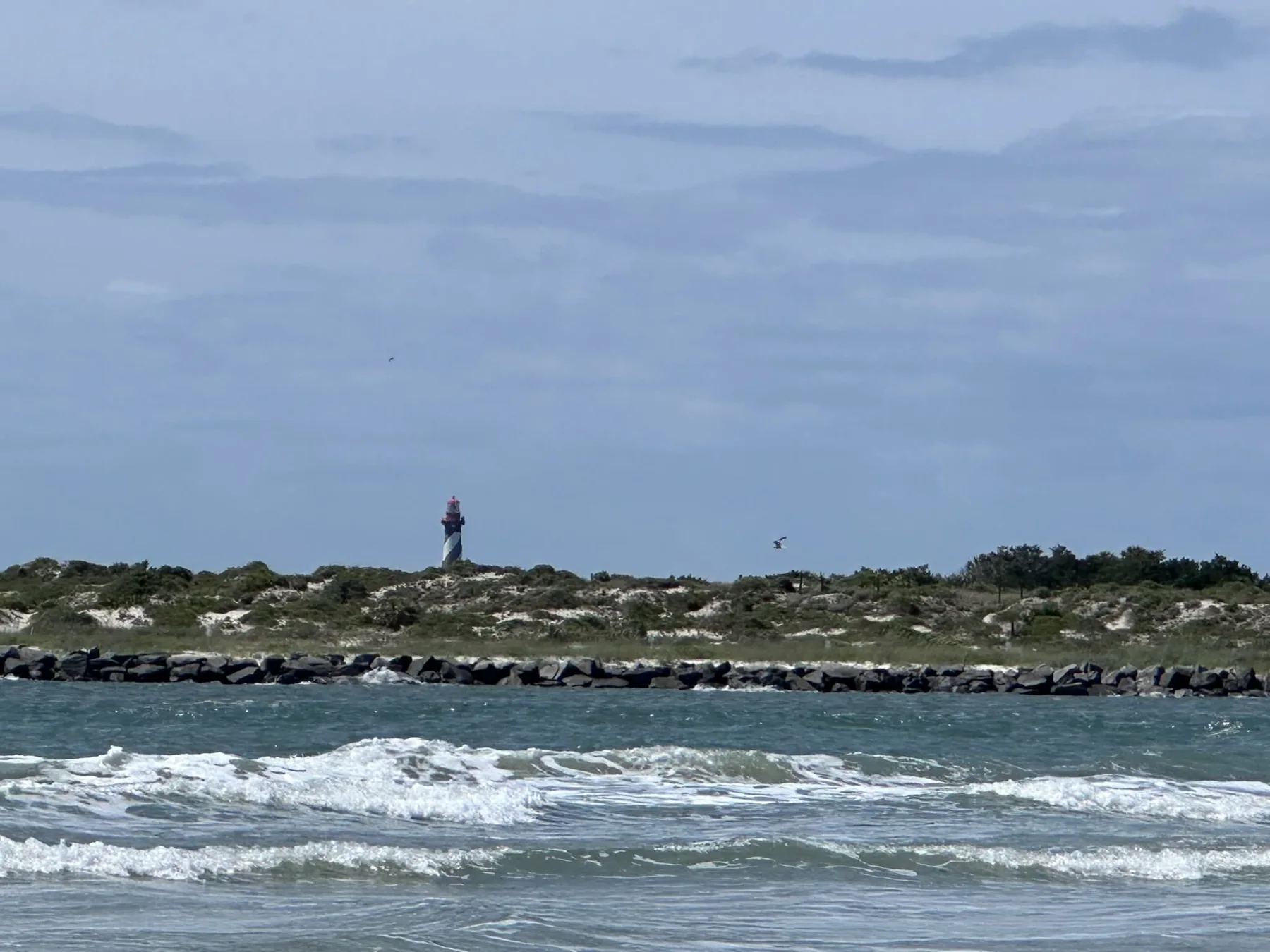 Lighthouse beyond the inlet and breaking waves