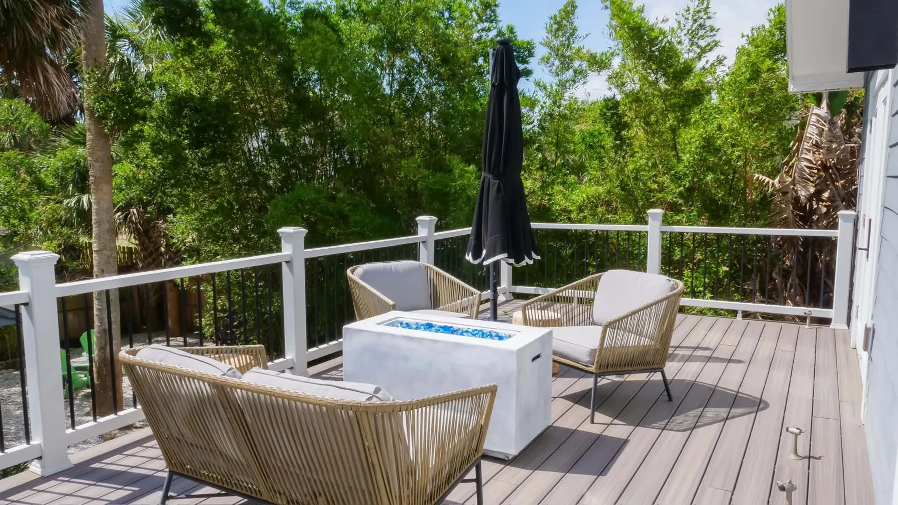 Sunlit deck at Hibiscus House, surrounded by palms and greenery